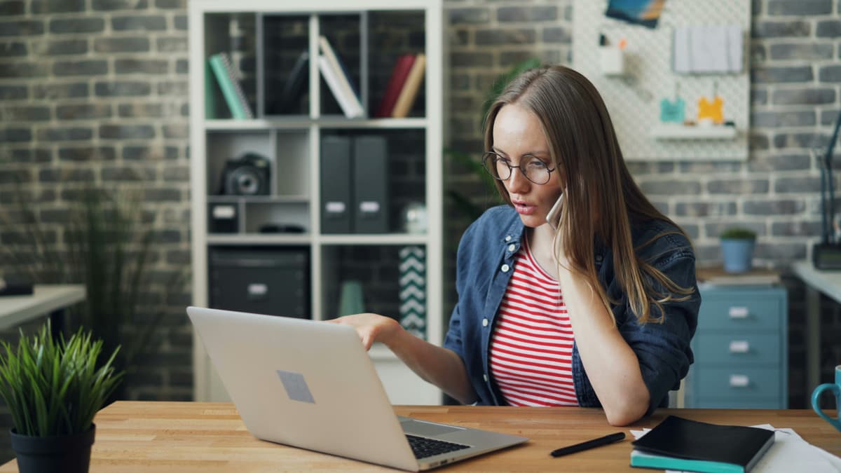 A woman speaking on the phone while working on a computer