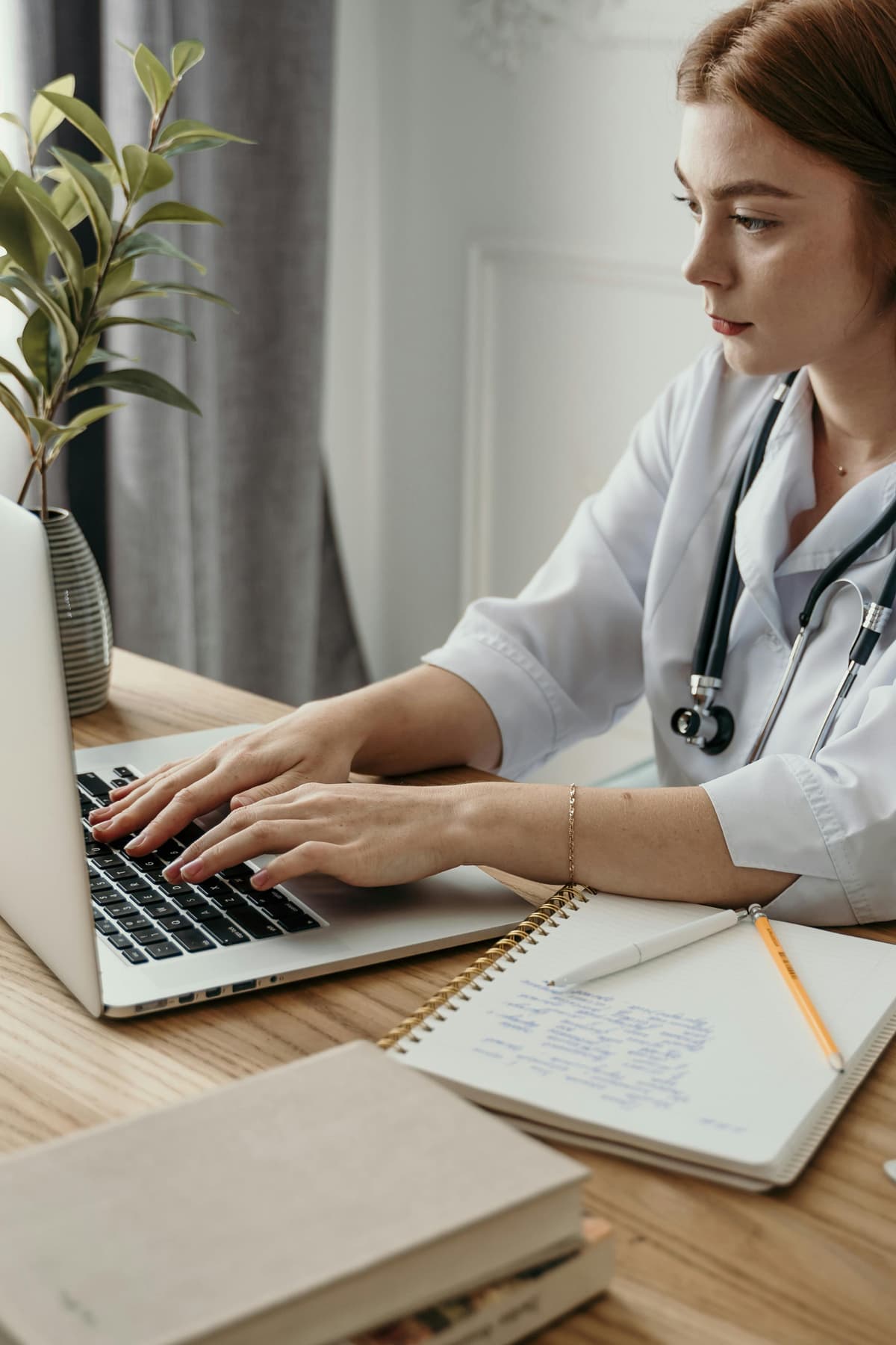 A woman doctor working with a computer and a notebook